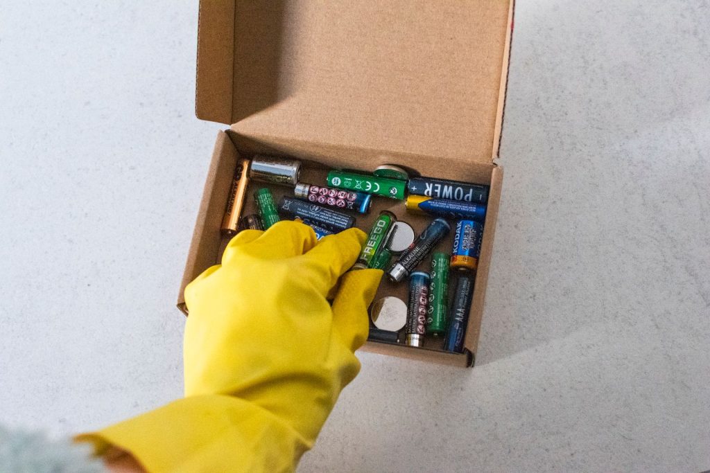 Gloved hand sorting used batteries for recycling