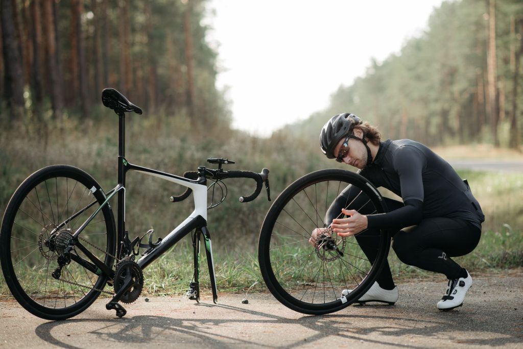 Cyclist fixing a bike wheel on a trail