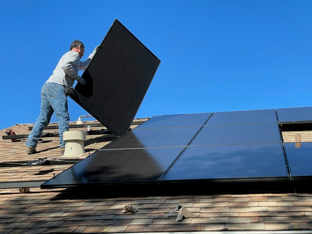 Installer mounting a solar panel on a shingled roof