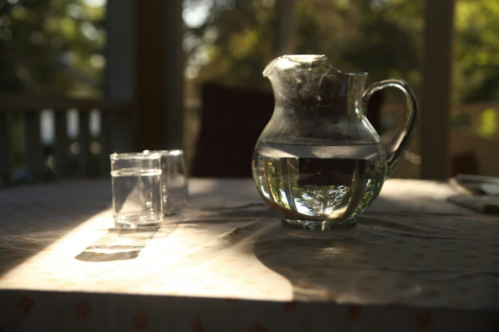 Glass water pitcher and drinking glass on a table