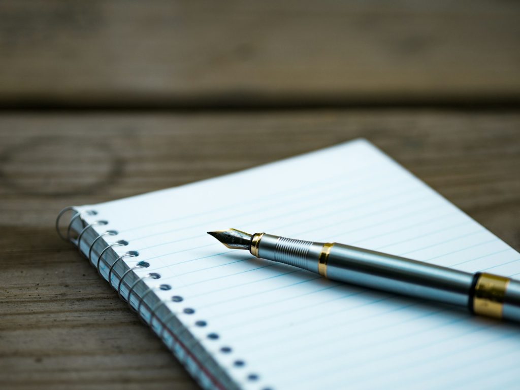 Fountain pen resting on a spiral notebook