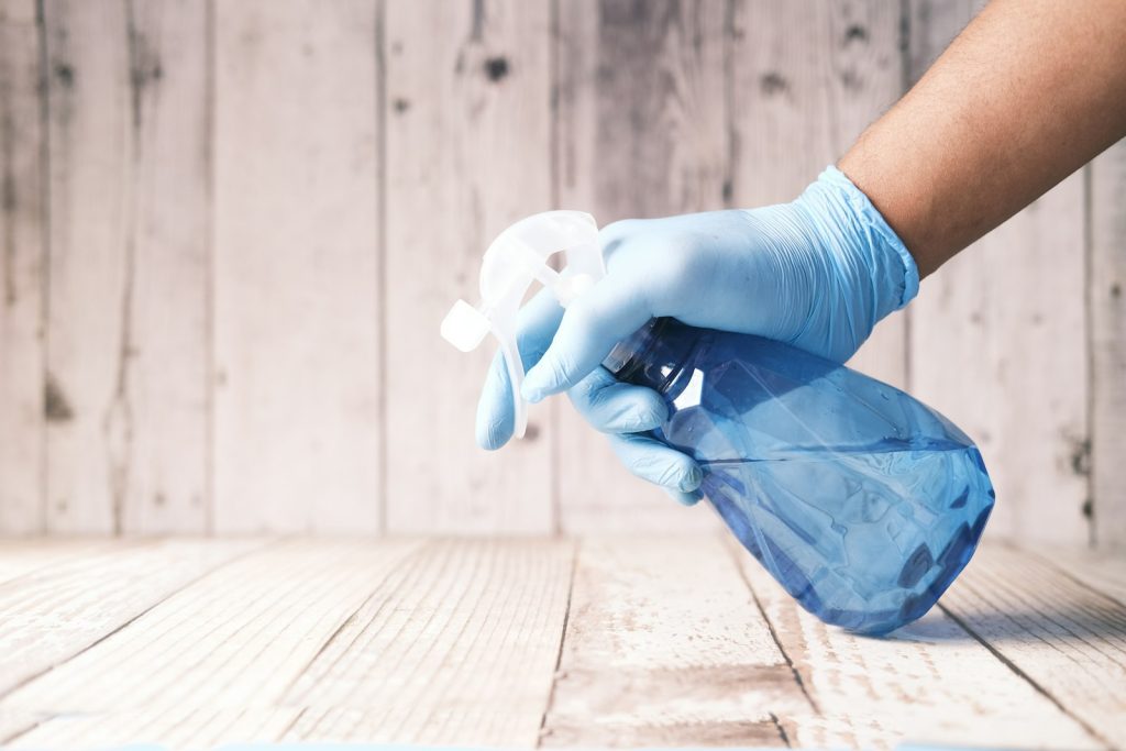 Gloved hand holding a cleaning spray bottle