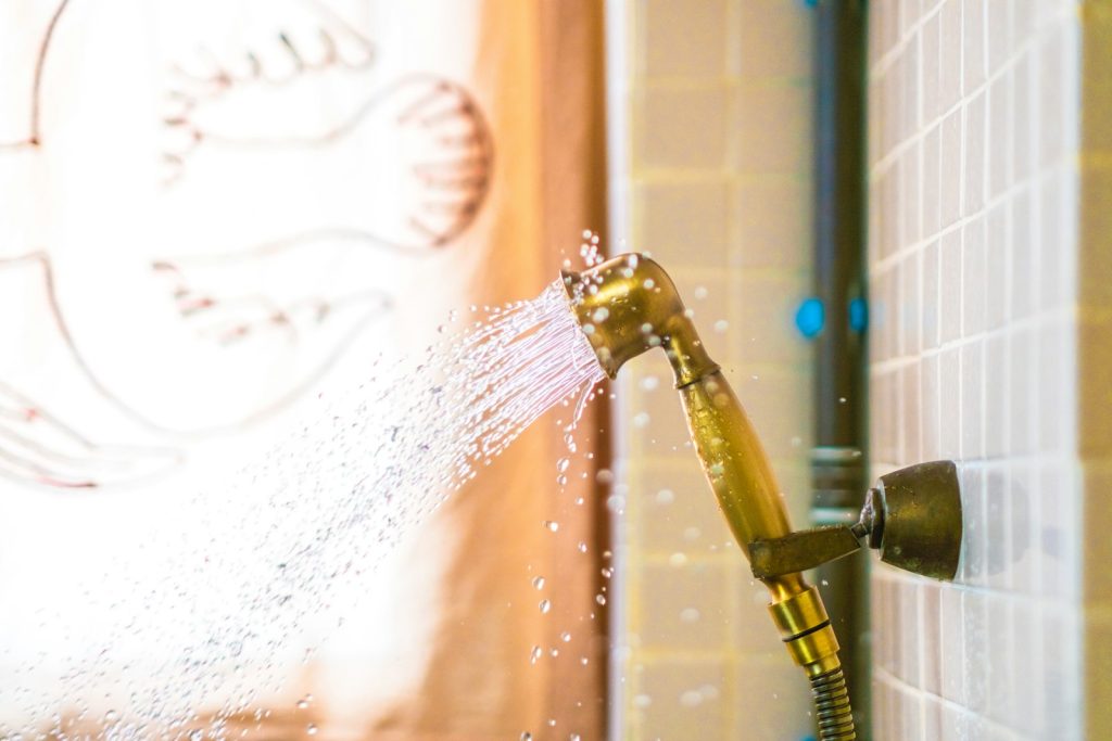 Shower head spraying water against a tiled wall
